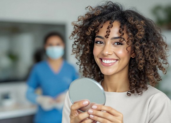 Woman smiling while holding small mirror