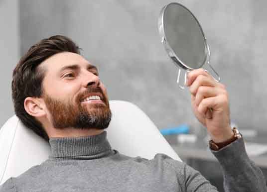 a patient checking his teeth with a mirror