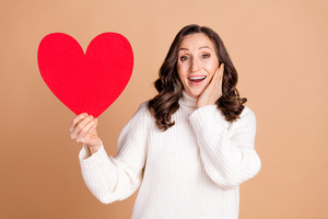 Woman holding up large paper heart and smiling